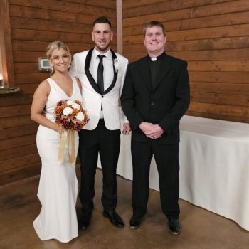 Bride and groom standing with their wedding officiant