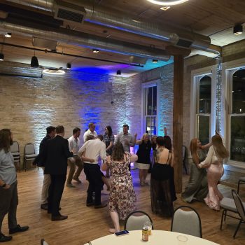 Wedding guests dancing with blue uplighting in a brick venue