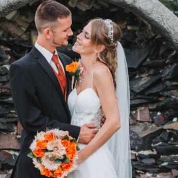 Outdoor wedding portrait of bride and groom with orange flowers