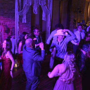 Guests dancing at a purple-lit wedding reception